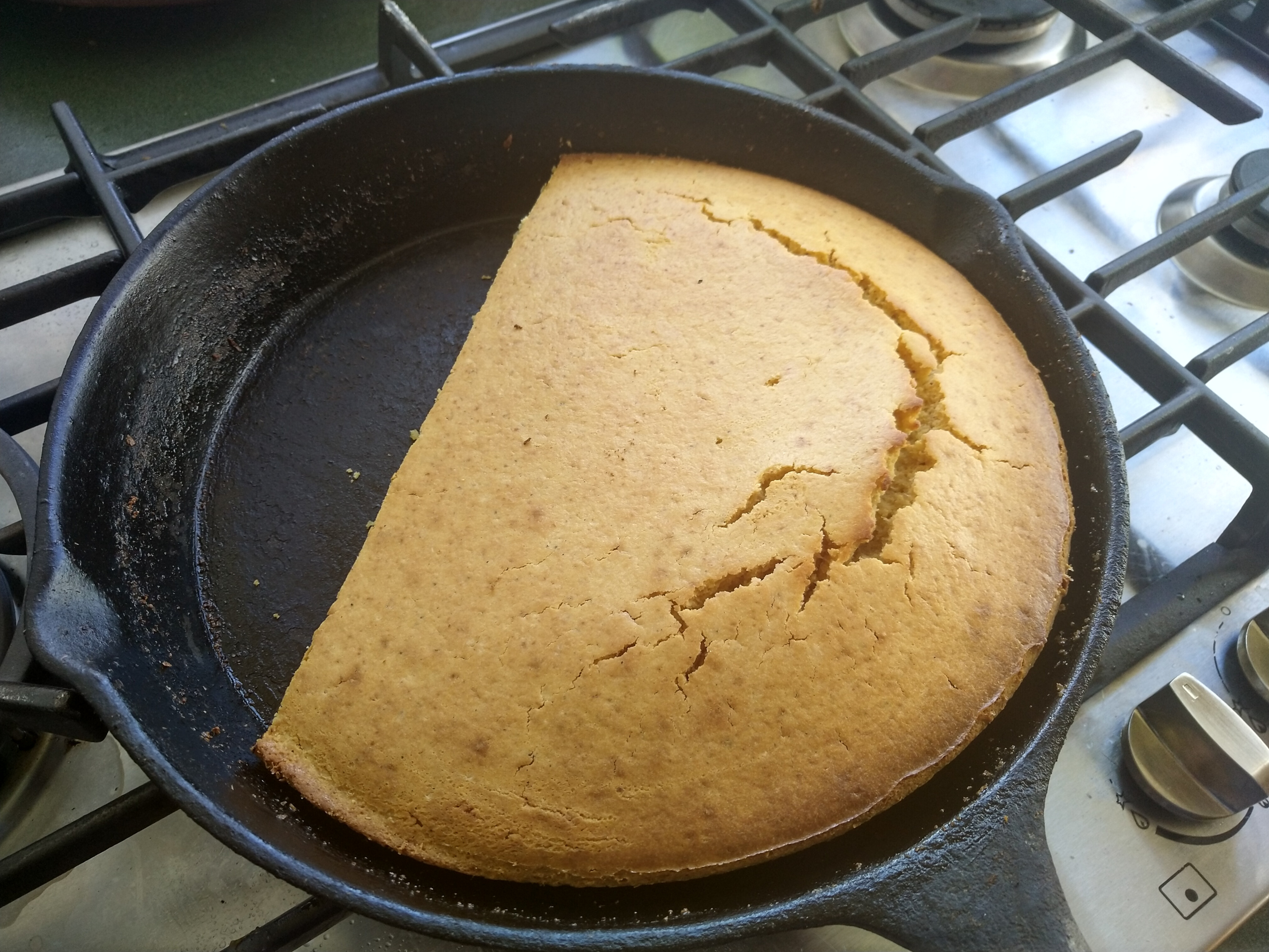 A cast-iron skillet, hot from the oven, cradling a golden-brown cornbread.