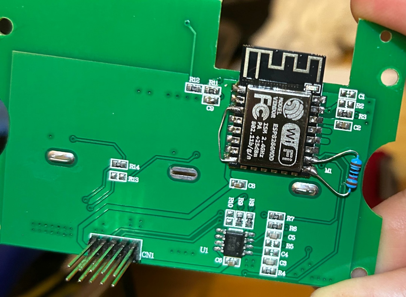 The PCB with an ESP-12F soldered in place of the WB3S, with a resistor bodged across two pads