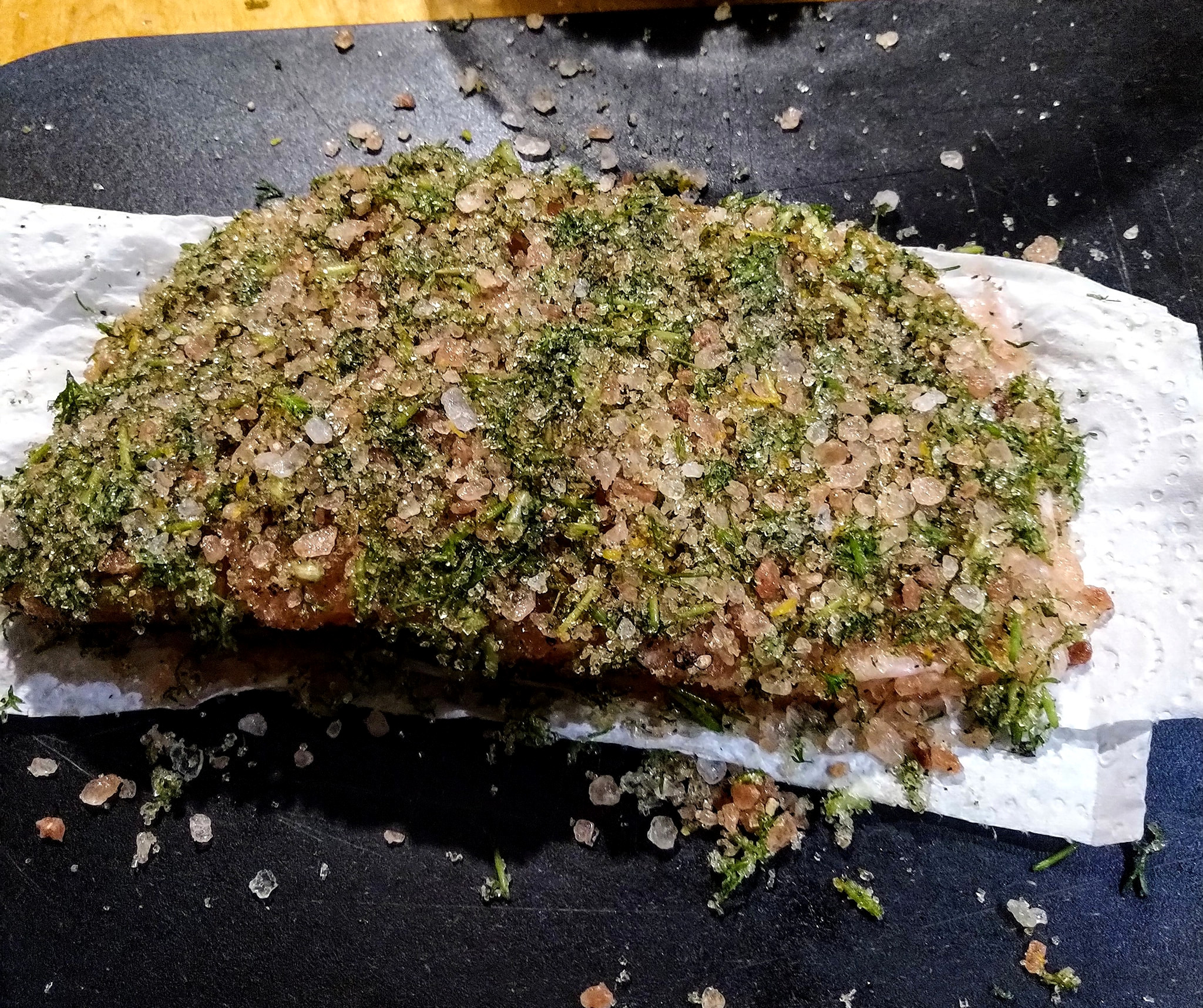 All ready to go into the vacuum sealer A slice of salmon, so covered in salt, sugar, and dill that the fish itself is invisible. Ready to be bagged.